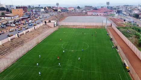 Aerial,-two-football-teams-playing-soccer-on-a-field-in-Yaonde,-Cameroon