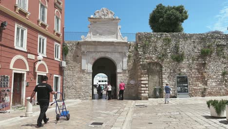 Old-town-Zadar-with-white-cobbled-street,-roman-gates-in-stonewalls-and-normal-life-going-on