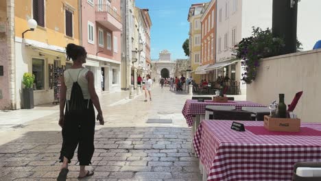 Verano-En-El-Casco-Antiguo-De-Zadar,-Calles-Empedradas-Blancas,-Arquitectura-Colorida,-Turistas-Asombrados-Caminando-Y-Mesas-De-Restaurante-A-Cuadros-Con-Letrero-Reservado