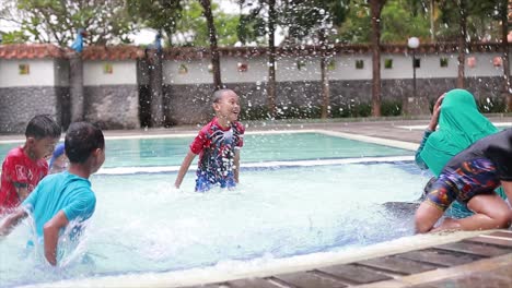 Children-play-in-the-swimming-pool-happily-and-happily-while-on-holiday-at-tourist-attractions-in-Indonesia,-unwinding-from-their-long-time-at-school