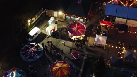 Illuminated-Christmas-fairground-carnival-in-neighbourhood-car-park-at-night-aerial-view