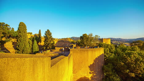 Timelapse-of-Sunlit-ancient-walls-and-trees-in-Málaga,-Spain-at-sunset