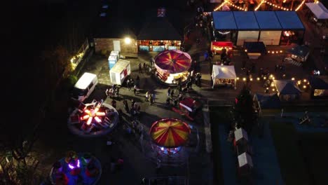 Illuminated-Christmas-fairground-attraction-in-neighbourhood-car-park-at-night-aerial-view