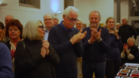 A-clapping-audience-consisting-of-white-gray-old-men-and-women-interior