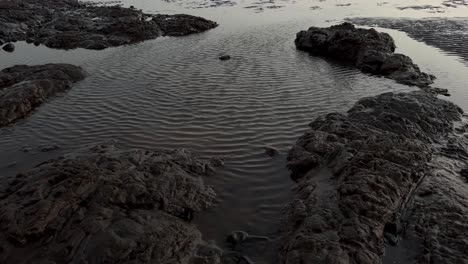 Luftdrohnenkamera,-Wunderschöne-Filmische-Aufnahme-Am-Strand,-Wo-Ves-Zurückgeht,-Nachdem-Er-Einen-Felsen-Im-Wasser-Getroffen-Hat