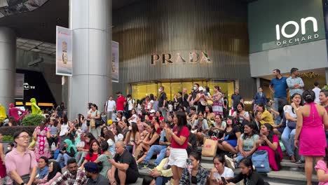 Crowd-of-people-siiting-outisde-shopping-mall-in-Orchard-Road,-Christmas-Eve-Celebrations-in-Singapore