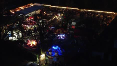 Illuminated-festive-Christmas-fairground-festival-in-neighbourhood-car-park-at-night-aerial-view