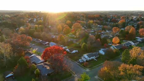 Autumn-trees-during-bright-fall-golden-hour-sunset-over-American-neighborhood-with-many-houses-and-homes