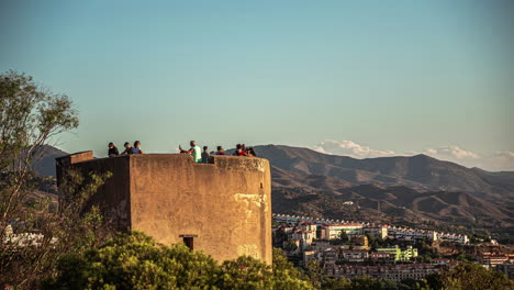 Timelapse-of-People-atop-an-ancient-watchtower-overlooking-Málaga,-Spain