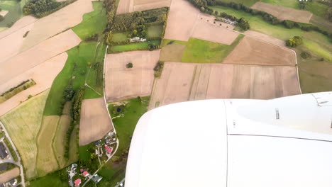 Countryside-Fields,-Town-Houses,-And-Jet-Engine-Seen-Through-The-Airplane-Window