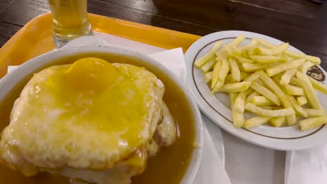 Savor-the-Portuguese-delight:-Francesinha-with-fries-and-an-Imperial—a-quintessential-culinary-experience-blending-flavors-and-traditions