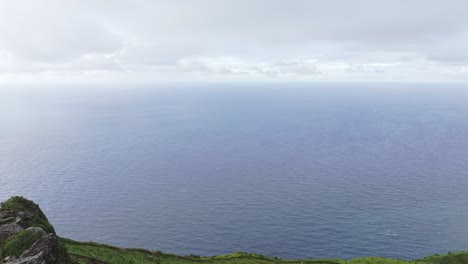 Man-adult-is-dancing-middle-of-nature-at-big-rock-in-Azores-island---Drone-shot
