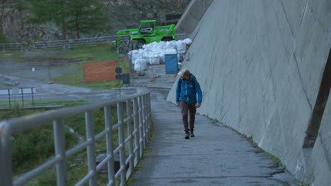 man-walking-along-a-concrete-path-and-a-metal-railing