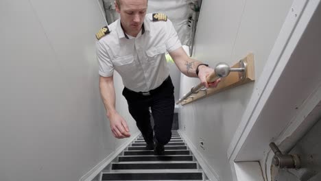 Captain-coming-from-ship-engine-room-and-walking-up-stairs-towards-camera