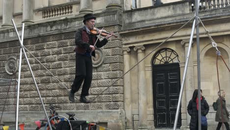 Ein-Performancekünstler-Spielt-Geige-Auf-Einem-Seil-In-Der-Innenstadt