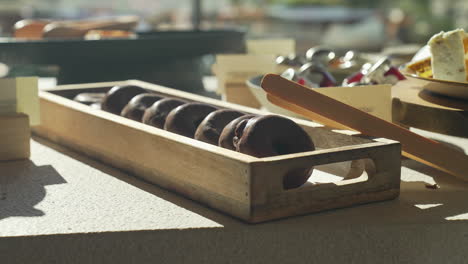 Frisch-Gebackene-Schokoladendonuts,-Präsentiert-Auf-Einem-Holzteller-Bei-Einem-Herrlichen-Und-Sonnigen-Morgenbrunch,-Sorgen-Für-Ein-Köstliches-Und-Optisch-Ansprechendes-Frühstückserlebnis