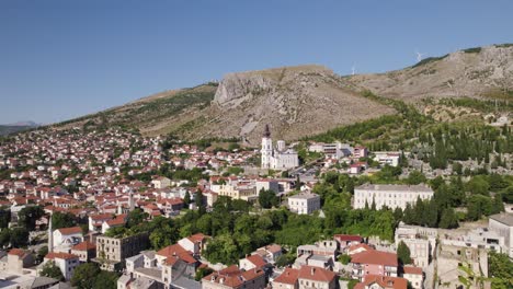 Luftaufnahme-Der-Stadtlandschaft-Von-Mostar-Mit-Der-Kathedrale-Der-Heiligen-Dreifaltigkeit-In-Der-Ferne,-Umlaufende-Aufnahme