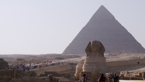 Spinx-face-on-the-background-of-the-Giza-pyramid,-tourists-on-tour,-Cairo,-Egypt