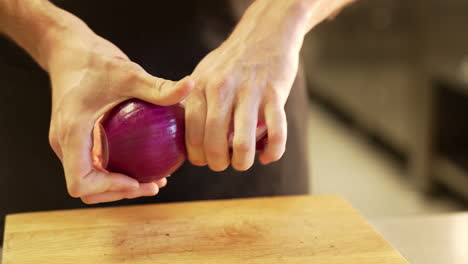 Chef-carefully-peels-onion-using-clean-hands,-demonstrating-precision-and-hygiene