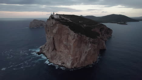 Cape-Caccia,-Sardinia:-aerial-view-in-orbit-of-the-lighthouse-of-this-famous-cape-and-the-waves-rolling-over-the-base
