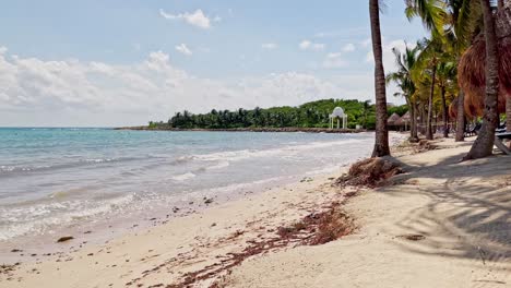 Trs-Beach-Resort-En-Tulum-Cancún-México-Mostrando-La-Playa-Y-El-Mar-Caribe-Con-Pequeñas-Olas-Y-Un-Cielo-Azul-Y-Algunas-Nubes-Blancas