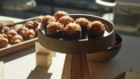Muffins-Recién-Horneados-Presentados-En-Un-Plato-De-Madera-Durante-Un-Delicioso-Y-Soleado-Brunch-Matutino,-Creando-Una-Experiencia-De-Desayuno-Deliciosa-Y-Visualmente-Atractiva.