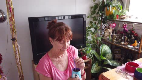 Eine-ältere-Argentinische-Frau-Trinkt-Allein-In-Ihrem-Haus,-Umgeben-Von-Grünen-Pflanzen,-Das-Traditionelle-Südamerikanische-Koffeinreiche-Kräutergetränk-Mate