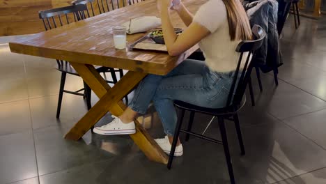 Girl-with-casual-clothes-having-lunch-alone,-while-using-her-cellphone
