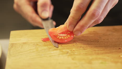 El-Chef-Pela-Cuidadosamente-Un-Tomate-Con-Un-Cuchillo-Sobre-Una-Tabla-De-Madera-Con-Las-Manos-Limpias,-Demostrando-Precisión-E-Higiene.