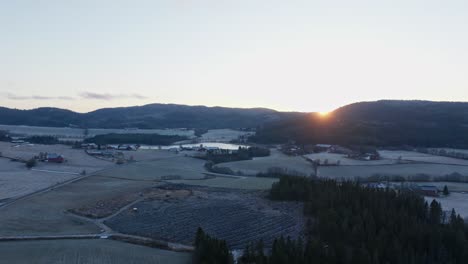 Ein-Blick-Auf-Den-Sonnenuntergang-über-Den-Bergen-Vom-Bauernhof-In-Indre-Fosen,-Kreis-Tröndelag,-Norwegen-–-Luftschwenk