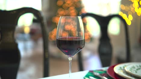 A-sliding-shot-captures-the-allure-of-a-red-wine-glass-against-a-mesmerizing-bokeh-backdrop,-a-toast-to-sophistication