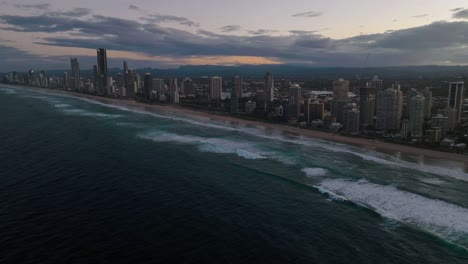 Gold-Coast,-Surfers-Paradise,-Queensland,-Australia,-drone,-as-night-approaches,-a-fly-over-as-waves-crash-at-this-beautiful-location