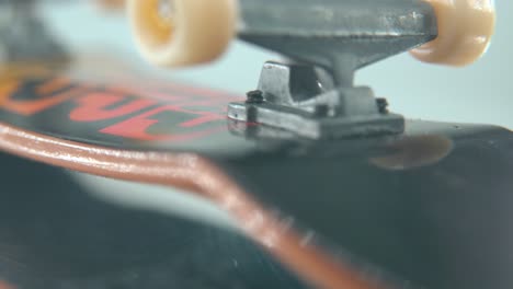 A-creative-macro-detailed-shot-of-a-mini-skateboard,-tiny-white-wheels,-upside-down-fingerboard-on-a-360-rotating-stand,-shiny-mirror-reflection,-professional-lighting,-cinematic-4K-video-tilt-up