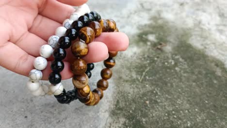 close-up-of-hand-holding-three-rosary-bracelets