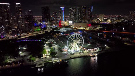 Night-urban-landscape-of-Skyviews-Miami-Observation-Wheel-at-Bayside-Marketplace-with-reflections-in-Biscayne-Bay-water-and-high-illuminated-skyscrapers-of-Brickell-at-night