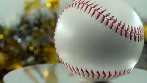 Cinematic-slow-close-up-shot-of-a-white-base-ball,-red-stitches-baseball-on-a-shiny-stand,-Christmas-blurry-decorations-in-the-background,-professional-studio-lighting,-4K-video-pan-right