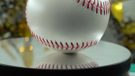Cinematic-slow-close-up-shot-of-a-white-base-ball,-red-stitches,-baseball-on-a-shiny-stand,-Christmas-blurry-decorations-in-the-background,-professional-studio-lighting,-4K-video-pan-right