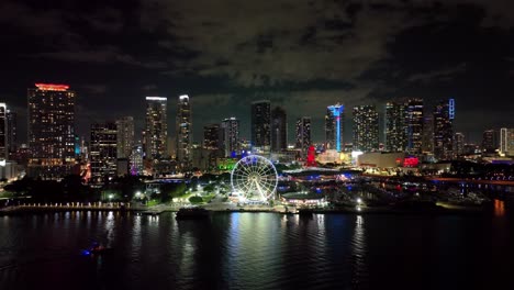 Distant-aerial-view-of-Downtown-Miami-with-waterfront,-marina,-and-Big-wheel-at-night