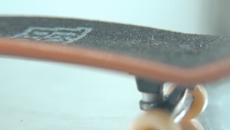 A-beautiful-macro-detailed-follow-shot-of-a-mini-skateboard,-tiny-white-wheels,-fingerboard-on-a-360-rotating-stand,-shiny-mirror-reflection,-professional-lighting,-cinematic-4K-video-pan-right