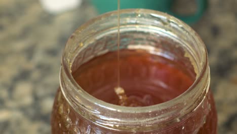 Close-up-view-of-a-spoon-taking-honey-from-a-jar