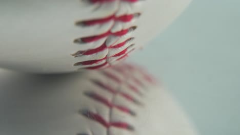 Cinematic-macro-shot-of-a-white-base-ball,-close-up-on-red-stitches,-baseball-on-a-mirror-reflecting-shiny-stand,-professional-studio-lighting,-4K-video-tilt-up