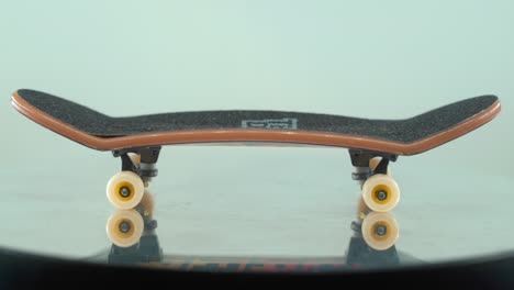 A-beautiful-detailed-close-up-shot-of-a-mini-skateboard,-tiny-white-wheels,-fingerboard-on-a-shiny-stand,-mirror-reflection,-professional-lighting,-cinematic-4K-video-tilt-up