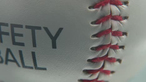 Cinematic-beautiful-smooth-macro-shot-of-a-white-base-ball,-close-up-on-red-stitches,-safety-ball,-baseball-on-a-shiny-stand,-professional-studio-lighting,-4K-video-pan-right