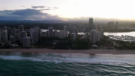 Gold-Coast,-Surfers-Paradise,-Queensland,-Australia,-drone,-sky-glowing-behind-the-luxury-high-rise-hotels,-sunset-at-Australia’s-playground