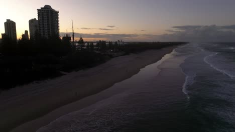 Gold-Coast,-Surfers-Paradise,-Queensland,-Australia,-drone,-just-as-evening-breaks,-waves-breaking-on-sunset-coloured-beaches