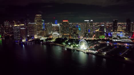 Aerial-view-of-Sky-views-Miami-Observation-Wheel-at-Bayside-Marketplace-with-high-illuminated-skyscrapers-of-Brickell,-city's-financial-center