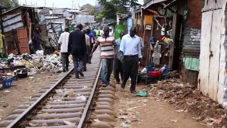 Men-walking-along-railway-in-Kibera,-Kenya