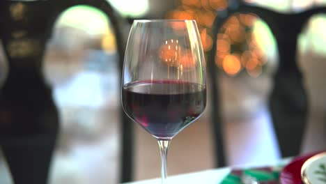 An-orbital-shot-captures-the-allure-of-a-red-wine-glass-against-a-mesmerizing-bokeh-backdrop,-a-toast-to-sophistication