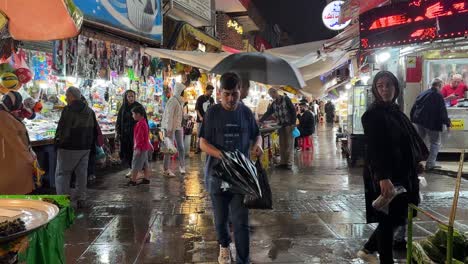 Family-shopping-at-night-light-rain-drops-in-traditional-bazaar-local-farmer-market-in-Iran-Rasht-Gilan-midddle-east-asia-people-life-in-persian-culture-historical-grand-bazaar-in-northern-countryside