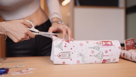 Low-angle-frontal-of-caucasian-female-hands-wrapping-a-Christmas-present,-slomo